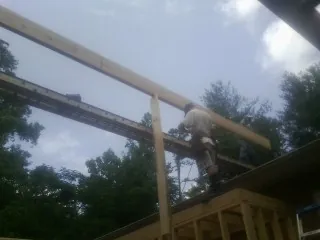 Carpenter setting a ridge beam over a new addition frame — Ice Dam Removal by Roofing Brothers in Buena