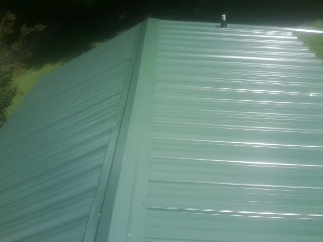 New green metal panels meeting at the ridge of a roof — Flat Roof Repair work by our crew in Buena