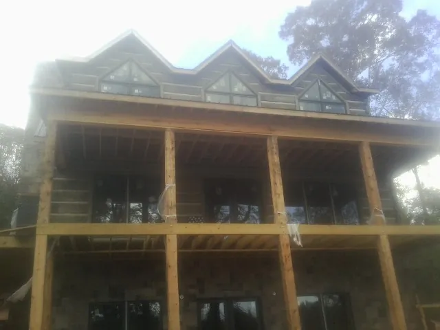 Dormers and porch framing on a large log home under construction — Roof Coating work by our crew in Buena