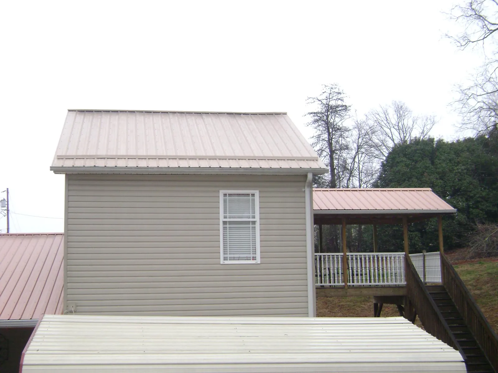Tan metal roofs on a two story addition and attached porch, from a Roof Replacement job in Buena